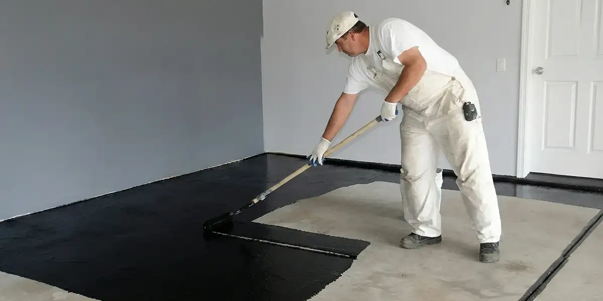 basement waterproofing professional applying waterproof coating to protect a basement floor in Seattle, WA